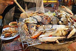 Thai seafood comprising shrimp, shellfish, crab are placed on the gril