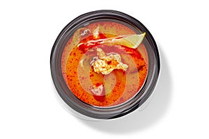 Thai soup tom yum gai with chicken, red pepper and fragrant spices served with lemon