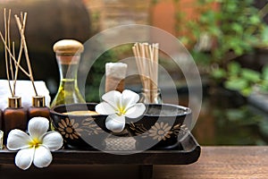 Thai spa composition treatments aroma therapy with candles and Plumeria flowers on wooden table close up.