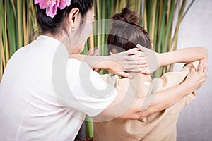 Thai Spa masseur is stretching women shoulder in Thai massage