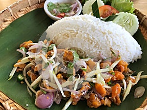 Thai spicy salad with rice on wooden table, Thai food.