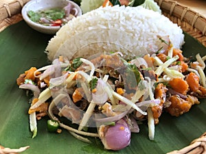 Thai spicy salad with rice on wooden table, Thai food.