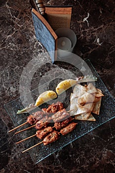 Thai spicy tender pork barbecue skewers with grill pineapple and Papadum crispy chips in glass plate