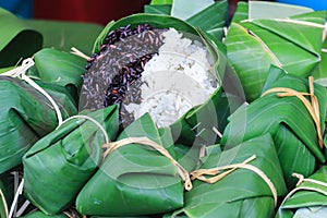 Thai steamed black and white sticky rice wrapped in banana leaf package