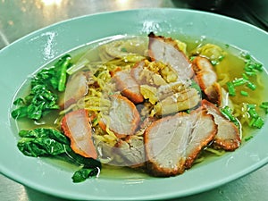 Thai style BBQ grilled honey pork and crab meat noodle soup with hot broth served in blue bowl