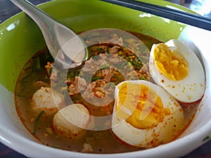 Thai style chopped pork noodle garnished with pork balls and half-cutted boiled egg photo
