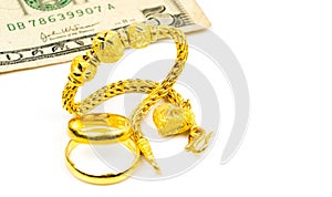 Thai style gold jewelry bracelet, couple gold ring and dollars bill isolated on white background with copy space