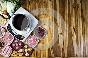 Thai style hot pot with delicious food ingredient on wood background and space for text