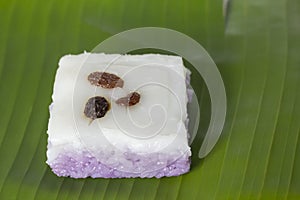 Thai sweet sticky rice cake with coconut milk and currant topping on banana leaf.