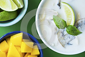 Thai Tom Kha Gai soup with mango and lime on green table