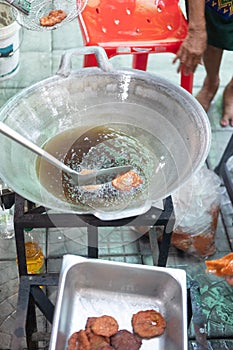 Thai vendor cooking deep fried fish paste ball in a big pan