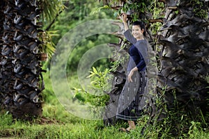 Thai woman in the countryside traditional costume portrait under the sugar palm trees row, thailand