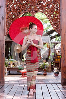 Thai woman dressed in traditional Northern Thailand culture costume holding a paper umbrella