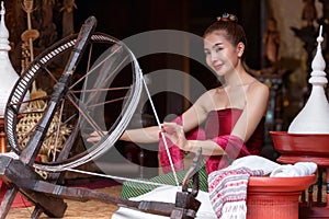 Thai woman dressed in traditional Northern Thailand culture costume spinning a thread. Identity culture of Thailand