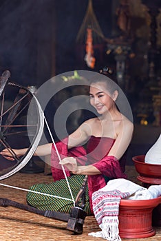 Thai woman dressed in traditional Northern Thailand culture costume spinning a thread. Identity culture of Thailand