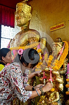 Thai Woman glid cover angel statue with gold leaf at Phra Kal Sh