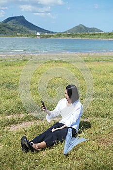 Thai woman playing smartphone on grasses field