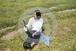 Thai woman playing smartphone on grasses field