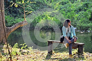 Thai woman portrait sit on bench at forest in Suan Phueng