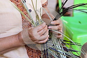 A Thai womanÂ´s hand is weaving an ancestral basket case from bamboo. People are demonstrating weavinga traditional basket made