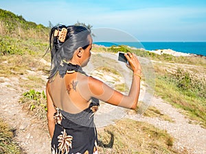 Thai woman is taking a photo at the coast of Thailand
