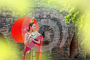 Thai Woman In Traditional Costume with umbrella of Thailand. Female Traditional Costume with thai style temple background. Wat