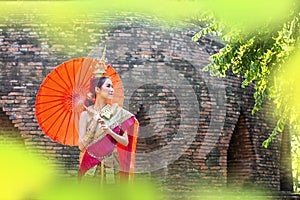 Thai Woman In Traditional Costume with umbrella of Thailand. Female  Traditional Costume with thai style temple background. Wat