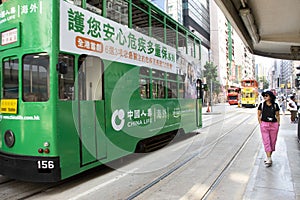 Thai woman walking go to bus station for passenger retro and vintage tram in Hong Kong, China