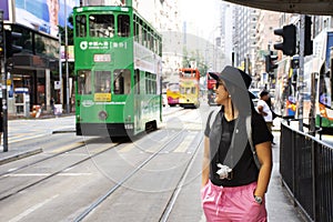 Thai woman walking go to bus station for passenger retro and vintage tram in Hong Kong, China