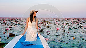 Thai women in a boat at the Red Lotus Sea Kumphawapi full of pink flowers in Udon Thani Thailand.