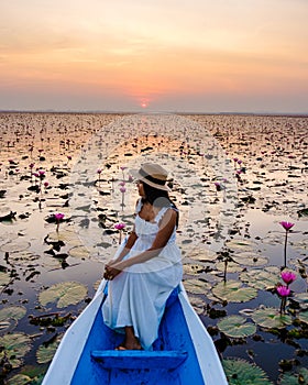Thai women in a boat at the Red Lotus Sea Kumphawapi full of pink flowers in Udon Thani Thailand.