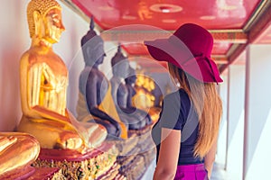 Thai women with hat looking at a rows of buddhas in Wat Pho temple in Bangkok , Thailand