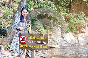 Thai women point to forbidden to swim sign in this area contradiction