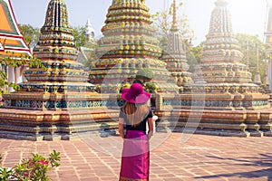 Thai women with traditional clothes standing in fornt of stuppas in Wat Pho temple in Bangkok in day , Thailand
