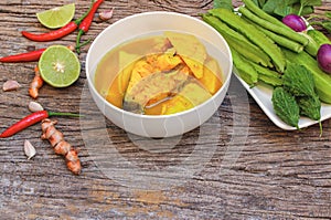 Thai Yellow curry with fish in a white bowl on a wooden table