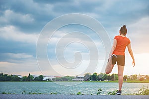 Thai young fitness woman runner stretching legs before run at park