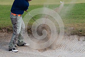 Thai young man golf player in action swing in sand pit during practice before golf tournament at golf course