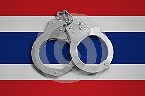 Thailand flag and police handcuffs. The concept of observance of the law in the country and protection from crime