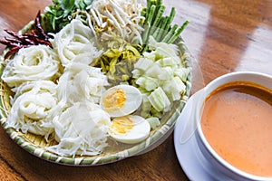 Thailand food vermicelli noodle boiled eggs and fresh vegetables on plate with curry soup bowl served wooden table - Thai rice