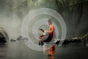 Thailand Little monk sitting on the creek or river in forest at