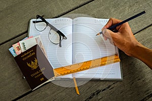 Thailand passport with money, yellow ruler, hand with pencil