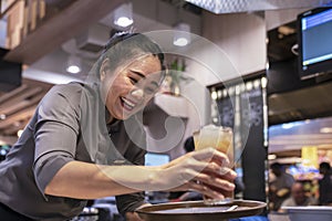 Thailand, Phuket, Patong. January 3, 2020: a smiling waitress serves a customer a glass with a cocktail and fruit juice. Good-