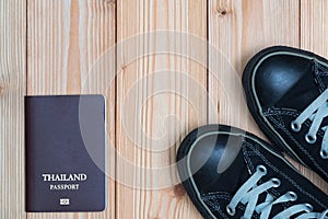 Thailand traveler`s Passport and sneakers ready to travel on wooden floor, top view with copy space, vacation concept
