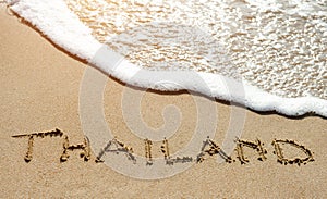 Thailand written on the sand beach near sea - travel holiday concept