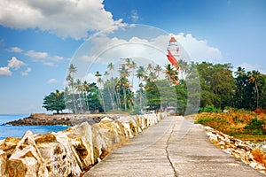 Thangassery Lighthouse on the cliff surrounded by palm trees and big sea waves on the Kollam beach. Kerala, India