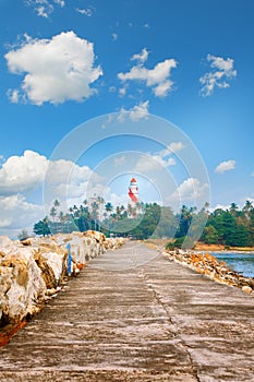 Thangassery Lighthouse on the cliff surrounded by palm trees and big sea waves on the Kollam beach. Kerala, India