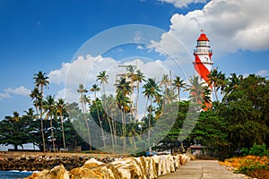 Thangassery Lighthouse on the cliff surrounded by palm trees and big sea waves on the Kollam beach. Kerala, India photo