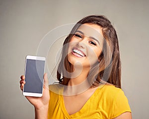 Thank goodness for the smartphone. an attractive young woman holding a cellphone with a blank screen against a grey