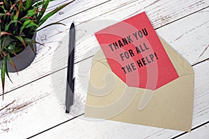 Thank you for all the help text on red card with envelope and pen on wooden desk