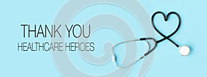 Thank you healthcare heroes message with stethoscope forming a heart on pastel blue background photo